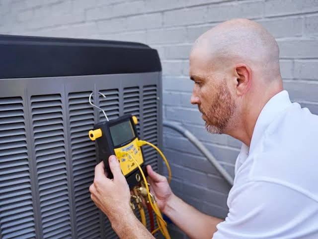 Technician checking an outdoor HVAC unit with a handheld diagnostic meter
